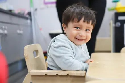 Toddler sitting in a high chair smiling