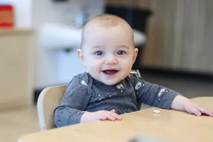  Early Learning Academy baby sitting in high chair and smiling